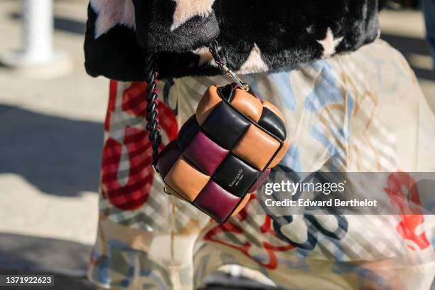 Guest wears a black with pale pink star print pattern fur coat, a pale yellow with black / red / blue print pattern long dress, a camel / black /...