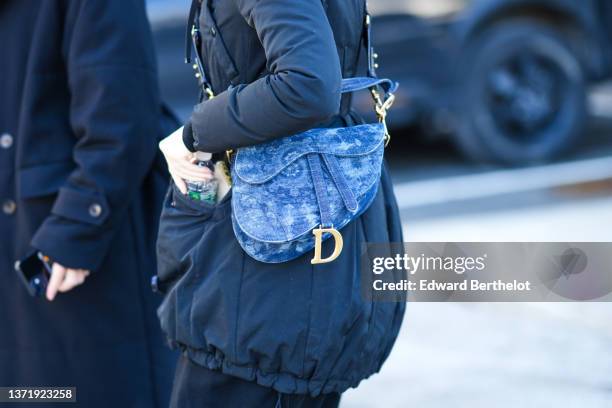 Guest wears a black puffer jacket, a blue denim print pattern Saddle shoulder bag from Dior, black pants, outside Gabriela Hearst , during New York...