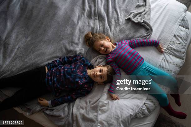 brother and sister lying on bed and enjoying - elevated view portrait stock pictures, royalty-free photos & images