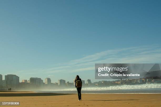 back view of woman walking on an urban beach - gijon ストックフォトと画像