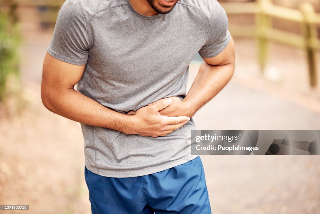 Shot of an unrecognisable man experiencing stomach ache while working out in nature