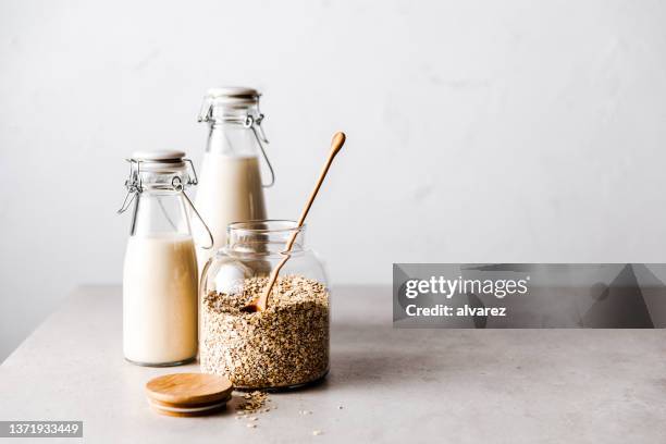 oats in a glass jar with oat milk bottles on table - jars kitchen stock pictures, royalty-free photos & images