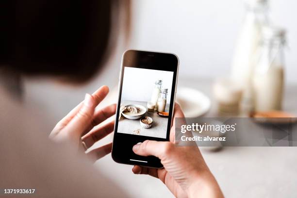 woman photographing freshly made oat milk - phone on table stock pictures, royalty-free photos & images