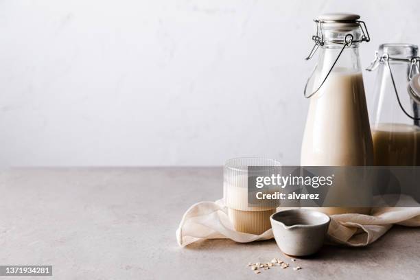 glas hafermilch auf dem küchentisch - hafermilch stock-fotos und bilder