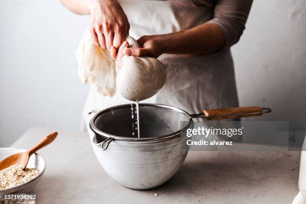close-up of a woman preparing vegan milk in kitchen - oat milk stock pictures, royalty-free photos & images