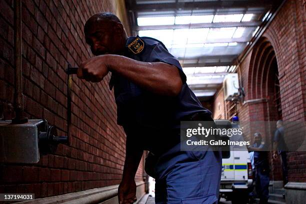 Police officer closes the gate to the Cape Town magistrates court to shield Dobrosav Gavric, a Serbian fugitive seeking refugee status in South...