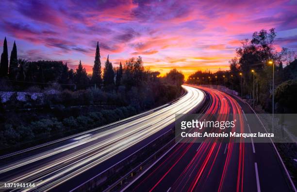 car light trails in a busy motorway on a sunset - vehicle light fotografías e imágenes de stock