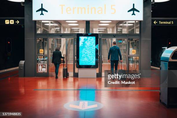 rear view of businessman and businesswoman entering airport from subway station - digitale beschilderung stock-fotos und bilder