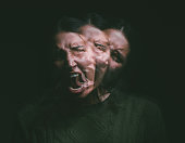 Studio shot of a young woman experiencing mental anguish and screaming against a black background