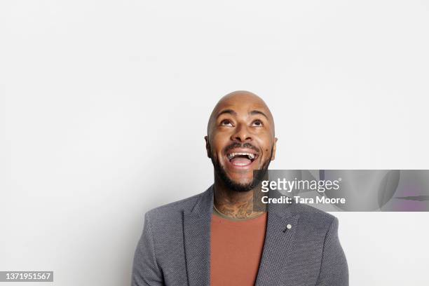 man smiling looking up against white background - man looking up photos et images de collection