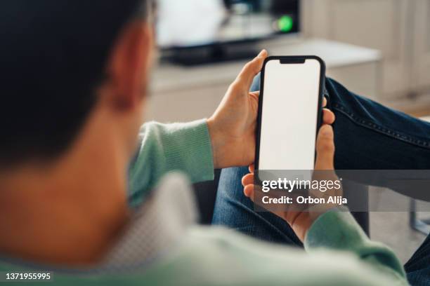 man using cellphone at home - hand holding mobile phone stock pictures, royalty-free photos & images