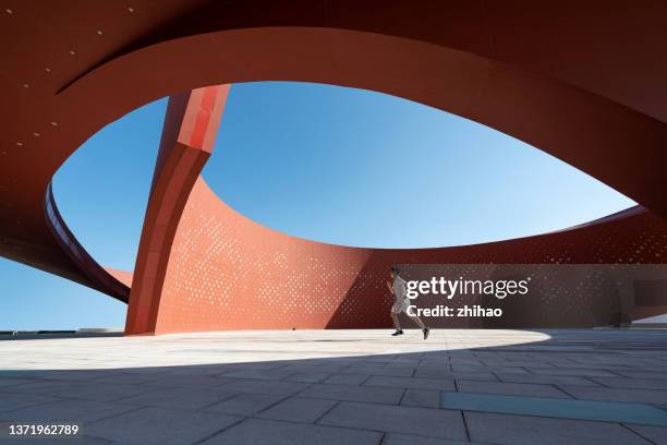 a person running in a red curved abstract architectural space - training center stock-fotos und bilder