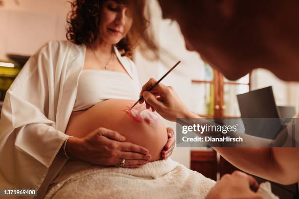 futuro padre pintando el vientre embarazada de su amada esposa - body art painting fotografías e imágenes de stock