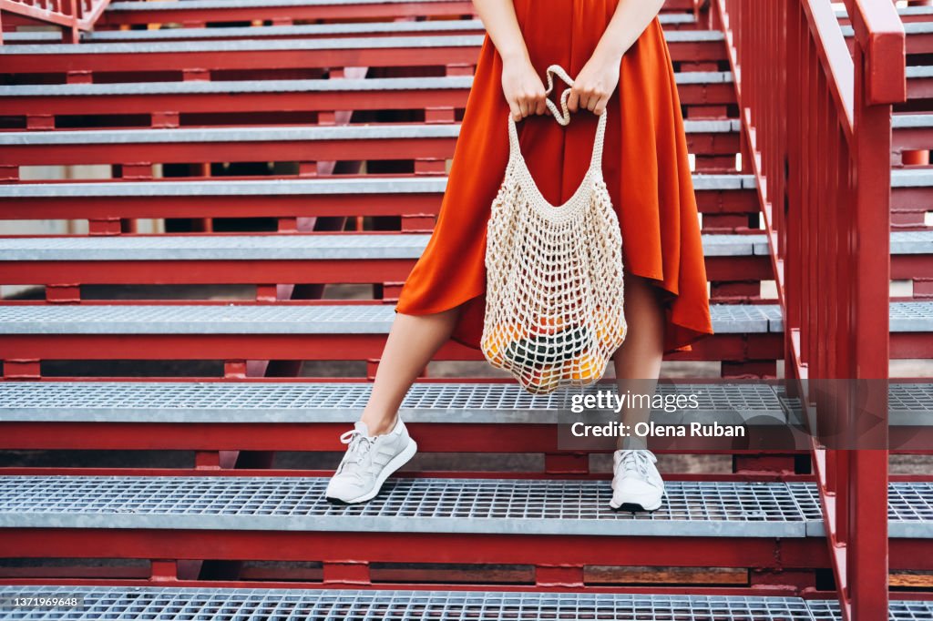 Young woman standing with shopping net bag.