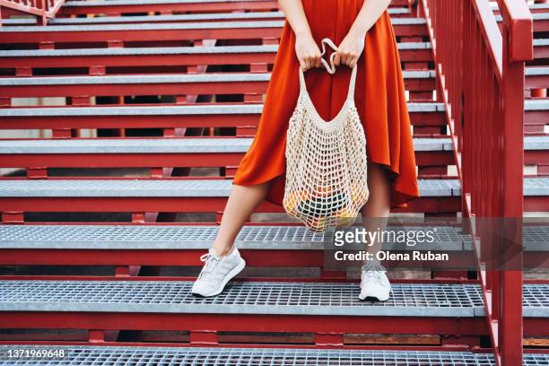 young woman standing with shopping net bag. - red shoe stock-fotos und bilder