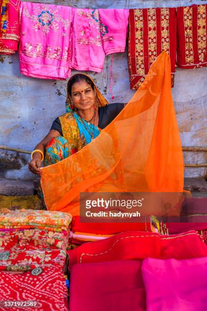 colors of india - woman selling colorful fabrics on local bazaar - rajasthani women stock pictures, royalty-free photos & images