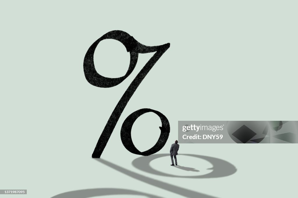 Man Staning In Shadow Of Large Percentage Sign
