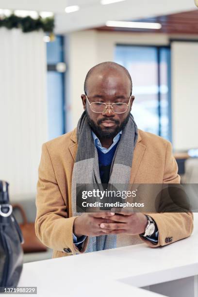 businessman reading a message at office hall - mediaphotos stock pictures, royalty-free photos & images