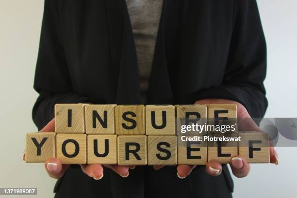 Business woman holding text insure yourself from wooden blocks