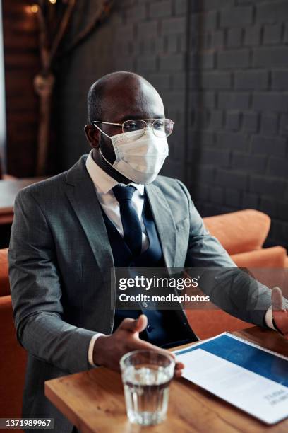 businessman in mask sitting at meeting - mediaphotos stock pictures, royalty-free photos & images