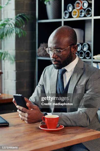 businessman using phone sitting in cafe - mediaphotos stock pictures, royalty-free photos & images