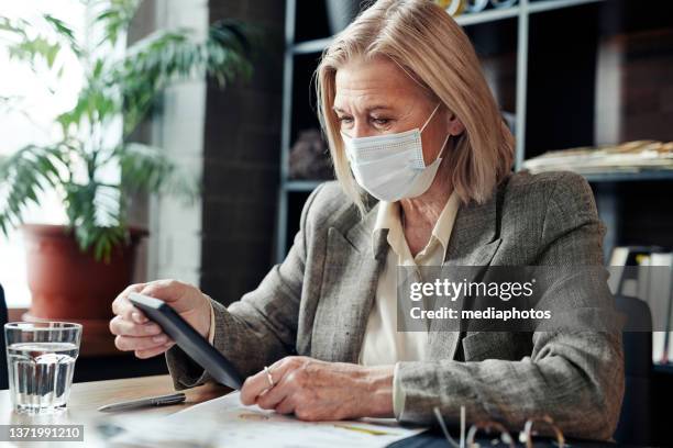 businesswoman in mask using phone at meeting - mediaphotos stock pictures, royalty-free photos & images