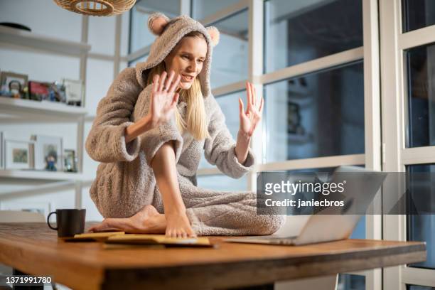 missing a friend during lockdown. woman doing video call in cute bear onesie - corona beer stockfoto's en -beelden