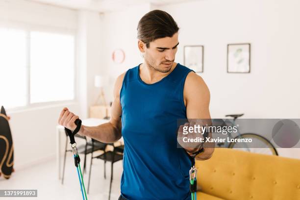 young man working out with stretching bands at home - ordinary guy stock pictures, royalty-free photos & images