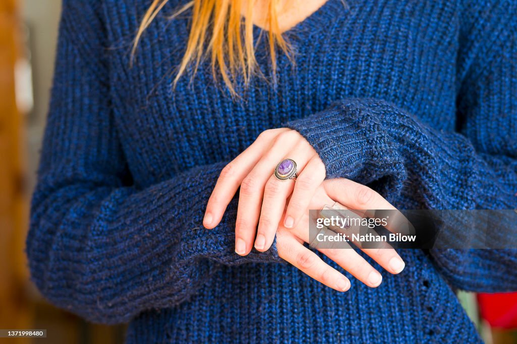 Young woman kneels down while crossing her wrists showing off her jewelry