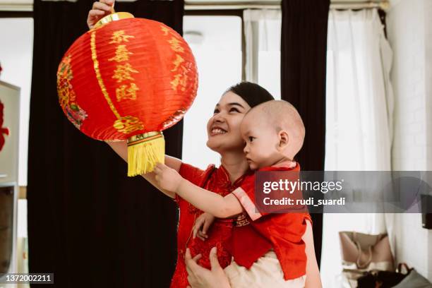 asian mother carrying her baby during imlek celebration - traditional clothing stock pictures, royalty-free photos & images