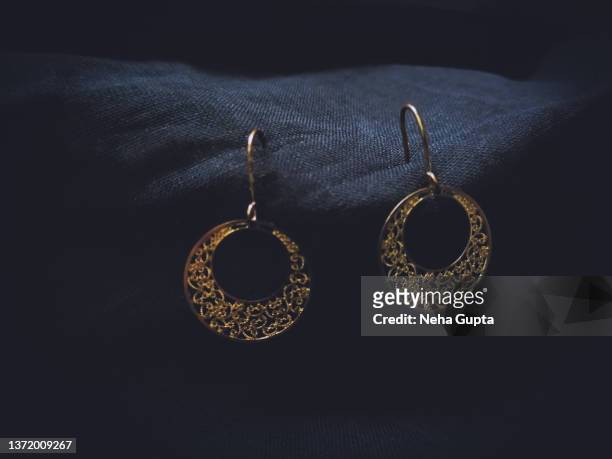 gold earrings on black fabric. - anhänger armband stock-fotos und bilder