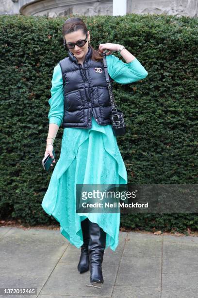 Guest wearing blue dress, channel puffer jacket, sunglasses, boots attends Roksanda at Tate Britain during London Fashion Week February 2022 on...