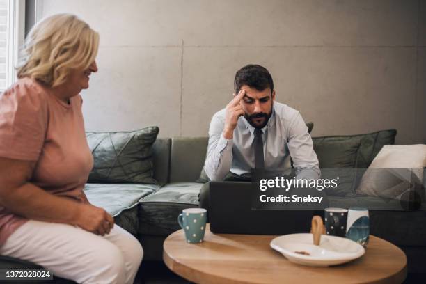 mother looking at her son trying to work - baby boomer millennial stock pictures, royalty-free photos & images