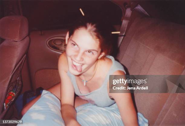 funny vintage road trip young woman making funny face in backseat of car - vintage car foto e immagini stock