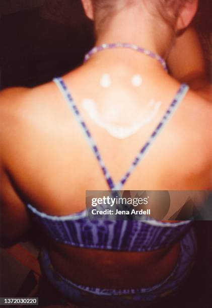 vintage 1990s happy smiley face sunscreen on young woman's back, y2k fashion y2k swimsuit - jaar 2000 stijl stockfoto's en -beelden