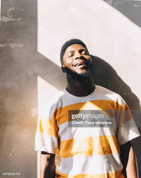 happy young african-american athlete is enjoying sun light at home - exhale stock pictures, royalty-free photos & images