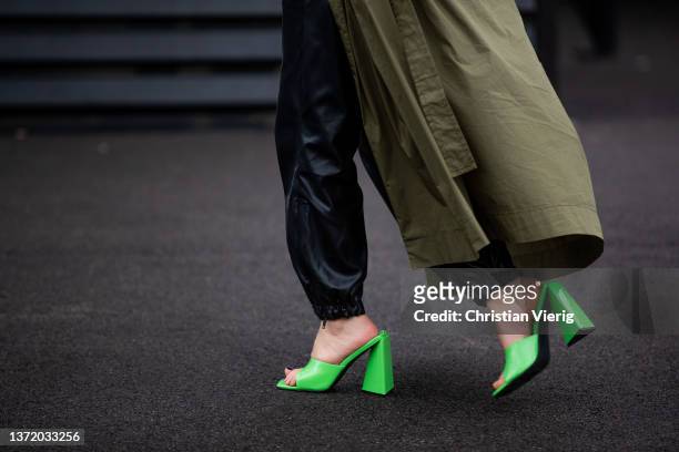 Guest is seen wearing neon top, black pants, olive trench coat, neon heels, black Jacquemus bag outside David Koma during London Fashion Week...