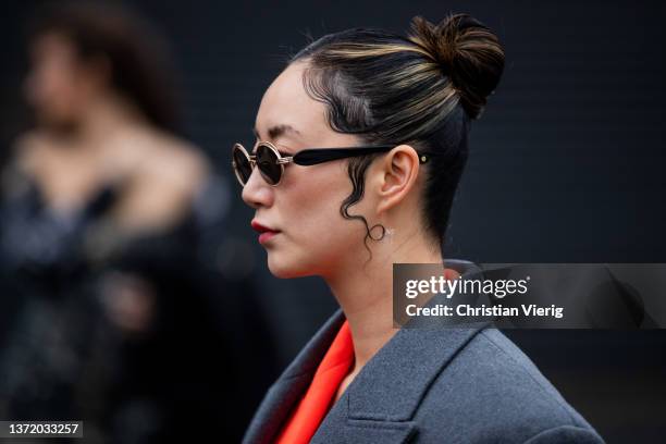 Betty Bachz seen wearing orange blazer, brown pants, grey oversized wool coat, sunglasses, wet styled hair outside David Koma during London Fashion...