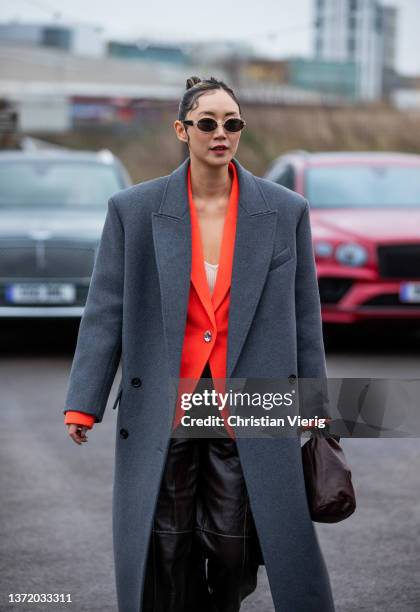 Betty Bachz seen wearing orange blazer, brown pants, grey oversized wool coat, sunglasses, wet styled hair outside David Koma during London Fashion...