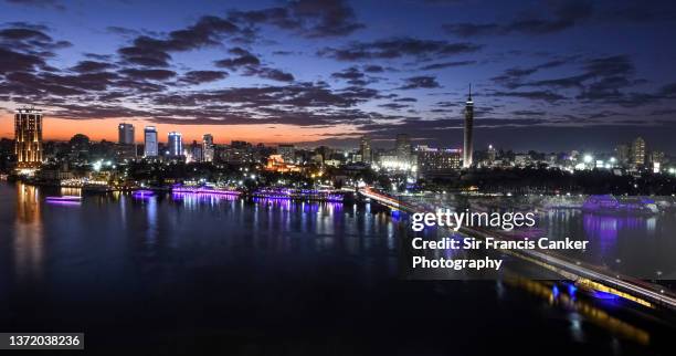 cairo skyline with nile river waterfront and zamalek district (gezira island)  with cairo tower and 6 of october bridge illuminated at dusk in cairo, egypt - cairo skyline stock pictures, royalty-free photos & images