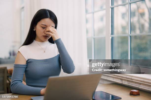 joven empresaria cansada frotándose los ojos después del trabajo - bloodshot fotografías e imágenes de stock