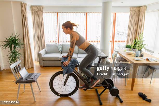 woman working out on her indoors cycling turbo trainer - pinning foto e immagini stock
