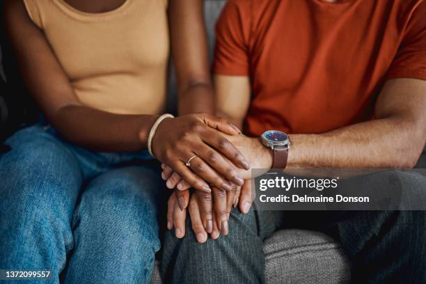 cropped shot of an unrecognisable couple sitting together on the sofa at home and holding hands - therapy stockfoto's en -beelden