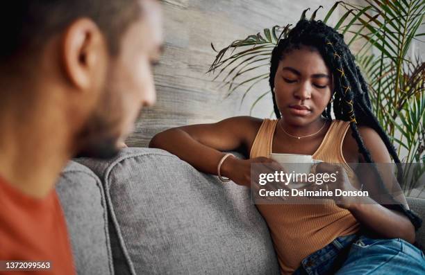 shot of an attractive young woman sitting with her boyfriend in the living room at home and looking upset - couple break up stock pictures, royalty-free photos & images