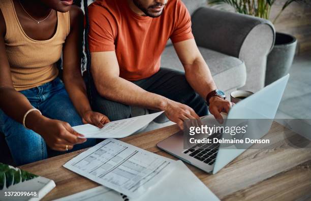 cropped shot of an unrecognisable couple sitting in the living room and using a laptop to calculate their finances - schulden stockfoto's en -beelden