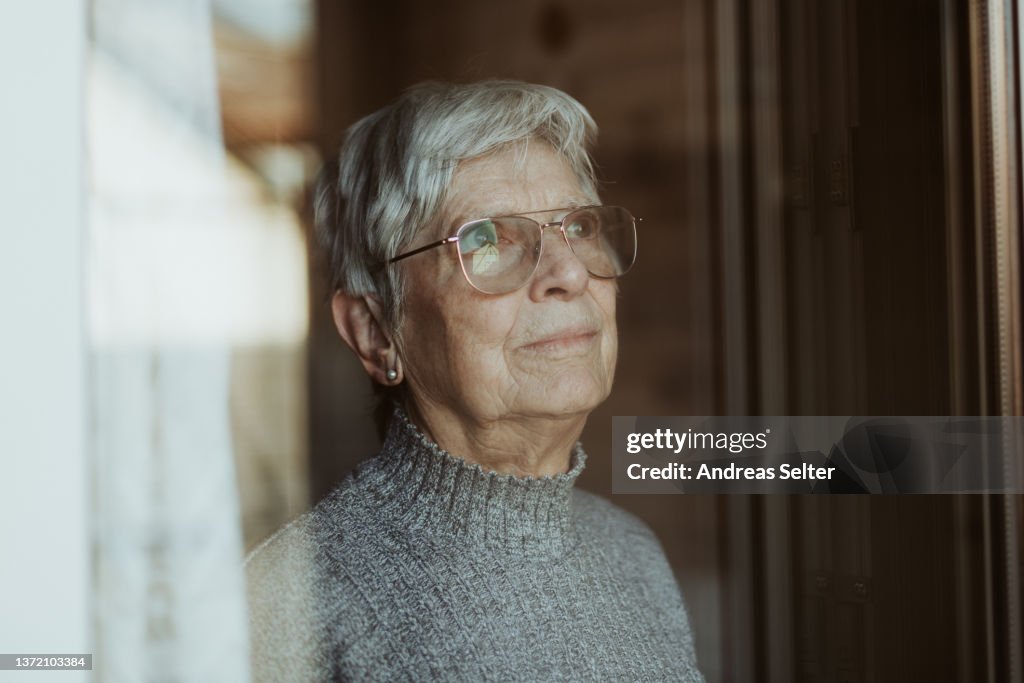 Elderly woman looking out of a window