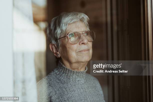 elderly woman looking out of a window - 70 79 år bildbanksfoton och bilder