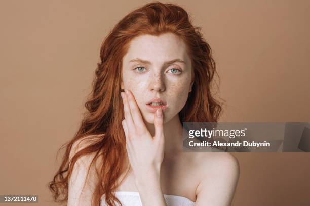 beautiful redhead woman portrait with freckles on brown background in studio with copy space. a lady advertises spa treatments. - beautiful redhead photos et images de collection