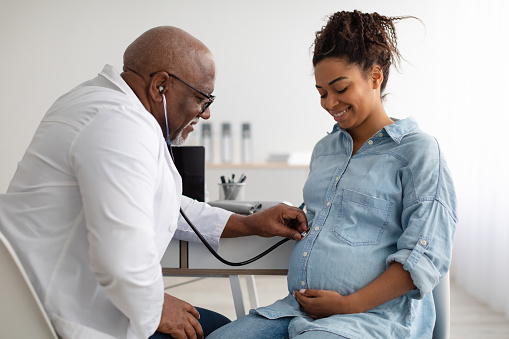 Male experienced doctor examining young pregnant woman