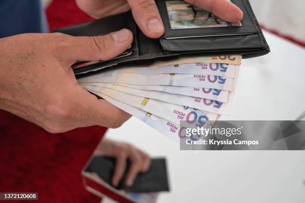man's hands holding wallet and colombian pesos bills - moedas imagens e fotografias de stock